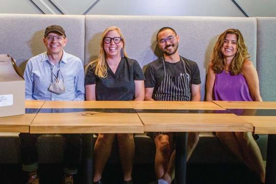 Four smiling people sit at a table.