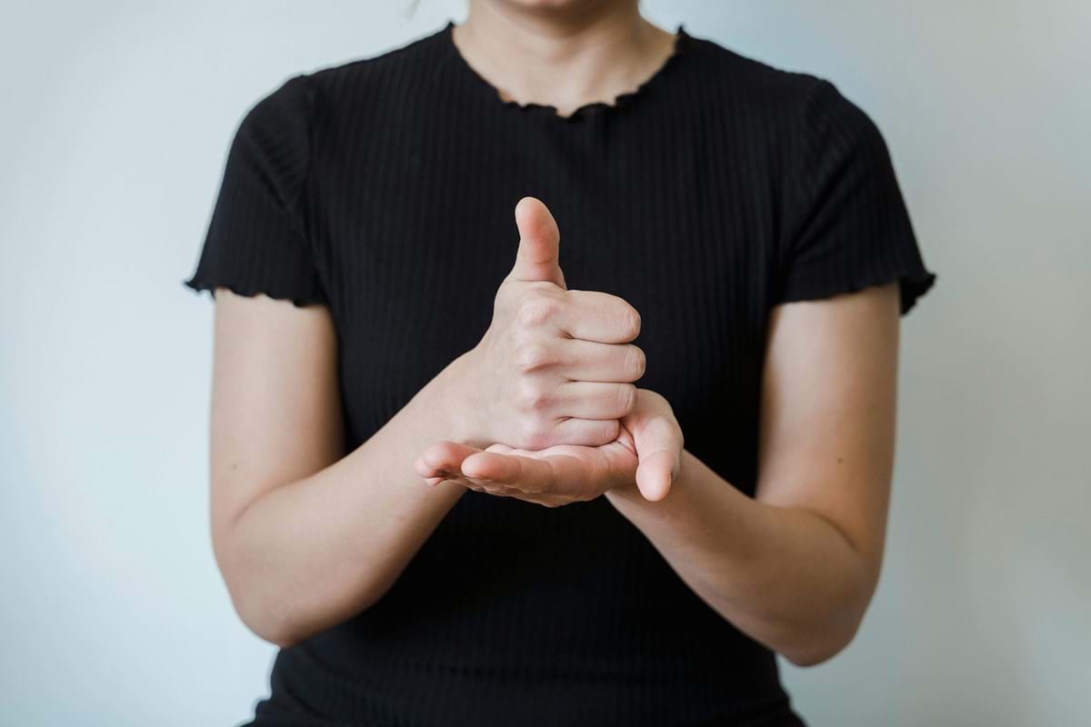Person wearing a black shirt and using sign language with a thumbs up.