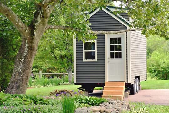 Tiny house on wheels with stairs leading to the door.